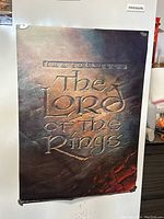 Classic Lord of the Rings title poster with textured look and dark color scheme mostly browns and reds.