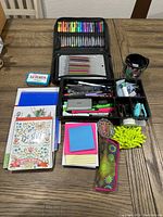 Top view of laid flat organizer with visible gel pens, colored pencils, and an assortment of sticky notes, a coloring book, and other office supplies.