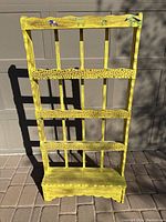 Front view of yellow distressed open-back shelf with cow stickers on top rail.