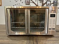 Front view of Oster stainless steel toaster oven with closed double glass doors and digital control panel on right side