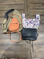 Lot of three bags including a tan crossbody sling, floral quilted clutch, and black clutch bag shown together on wooden surface.