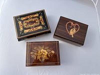 Photo of three Italian rectangular wooden music boxes with inlaid lid designs including floral and lovebirds