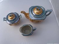 Photo displays all three pieces: teapot, sugar bowl with lid, and creamer on a white background.