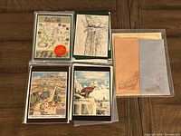 Full overview showing multiple sets of Tolkien postcards and stationery envelopes arranged on a wooden floor, including a Tolkien map postcard and illustrated scene cards.