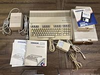 Full kit view showing the Commodore 128 computer, the two floppy drives (1581 and 1571), power supply, system guide and manuals, and system diskettes.