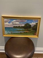 Full frontal view of the framed golf course landscape painting by William Rodgers showing the vibrant scenery with a golfer near the gulf shore.