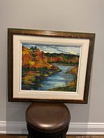 Front view of artwork showing entire autumn river landscape painting in frame.