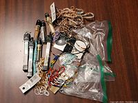 Overview photo showing an assortment of jewelry crafting materials including seed beads in various colors, chains, pendants, and wire scattered on a surface.