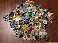 Top view photo showing a large pile of assorted pendants, brooches, and jewelry crafting pieces in various colors and shapes.