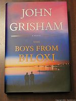 Front cover of John Grisham The Boys from Biloxi hardcover book, showing title, author, and sunset scene with silhouettes.