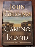 Front cover of hardcover John Grisham Camino Island first edition book showing title and author with boardwalk to beach image.