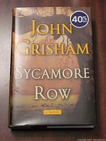 Front cover of John Grisham's Sycamore Row hardcover book with dust jacket showing tree image and title with author name in gold lettering.