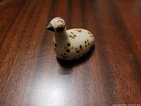 Side view of Mexican pottery bird figurine highlighting painted floral dot pattern and black beak