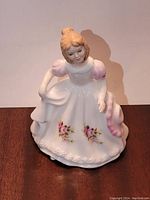 Front side of the Royal Doulton porcelain figurine depicting a girl in a white floral dress with pink roses.