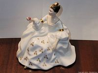 Front angle view of Royal Doulton 'My Love' feminine porcelain figurine dressed in white with gold accents and holding a pink rose.