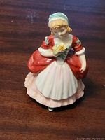 Front view of Royal Doulton Valerie HN2107 figurine showing the figure holding flowers, detailed dress with red and white colors
