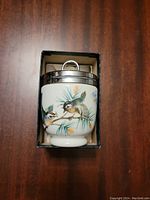 Porcelain egg coddler showing detailed colorful bird illustrations and metal lid inside original fitting box.