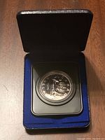 1976 Canadian silver dollar coin in protective capsule inside a blue-lined black box.