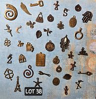 Photo showing all 40 bronze charms arranged on a blue surface for identification and condition assessment.