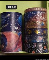 View of all 8 rolls of celestial-themed washi tape stacked in two columns showing varied cosmic designs, planetary names, stars, moons, and foil details.