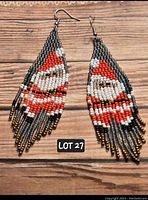 Pair of hand-beaded Santa Claus tassel earrings with nickel-free hooks laying flat on wooden surface.