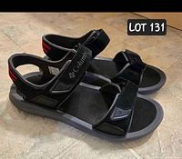 Side and front angle showing the overall design, material, and condition of the black Columbia sandals with Velcro strap closures.