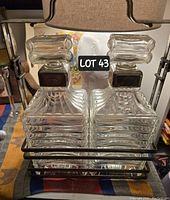 Two square-shaped ribbed glass decanters with large square stoppers and silver plated necks, shown side by side.