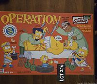 Box of The Simpsons edition Operation board game showing cartoon Homer Simpson and other Simpsons characters, with Lot 214 tag.
