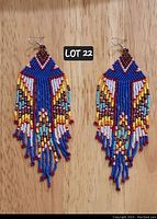 Photo of a pair of vibrant, multicolored hand-beaded tassel earrings with nickel-free hooks on a wooden surface.