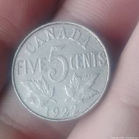 Reverse of 1922 Canadian 5 cent coin showing denomination, maple leaves and date.