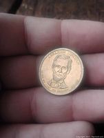 Gold-colored $1 coin featuring Abraham Lincoln's portrait on obverse.