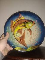 Front view of the circular plate showing detailed hand painted fish and aquatic plant design with bright majolica glaze.