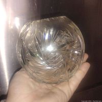 Pinwheel cut lead crystal ball vase held in hand to show size and clear glass cuts