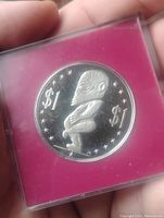 Reverse of coin showing traditional figure and denomination markings sealed in capsule.