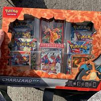 Front view of Charizard EX Premium Collection sealed box showing booster packs and promotional Charizard cards inside clear window packaging.