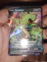 Close-up image of Tyranitar V Pokemon card showing the full art holographic foil design and card details.