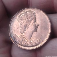 Obverse side showing Queen Elizabeth II crowned profile in copper medallion held in hand