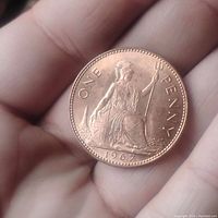 Obverse side of 1967 large penny coin showing Britannia seated with trident and shield, inscription 'ONE PENNY' and date '1967'.