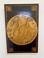 Front view of the Art Nouveau pyrography wall panel featuring Abundantia with cornucopia and bowl, black background and corner floral motifs.