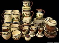 Image showing the full assortment of 48 pieces including mugs, pitchers, egg cups, pots, plates, and bowls, all decorated with hand-painted cottages and trees.