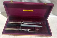 Carving set displayed open in maroon lined case showing knife, sharpening steel, and fork, along with Community Plate label.