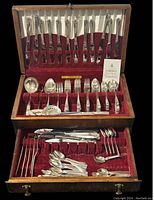 Image of vintage Community The Finest silverplate flatware set in wooden case with red velvet lining showing knives, forks, spoons, and serving utensils.