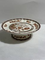 Side angled view showing the entire pedestal plate with scalloped edges and detailed India Tree pattern.