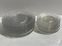 Stack of 8 inch vintage crystal plates and stack of 5 inch vintage crystal plates side by side on white surface.