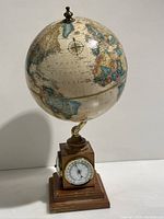 Front and globe view showing the 19-inch globe with vintage style map and compass rose details, mounted on brass arm above wooden base with barometer visible on the front face.