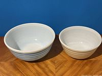 Front view of two Pyrex bowls showing interior and side colors and stripes.