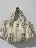 Front view of white leather handbag with braided handles and silver-tone button accents.