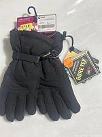 Front view of pair of black Kombi water-resistant gloves with adjustable wrist straps and attached Gore-Tex tag.