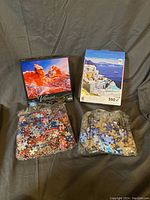 Two open boxes showing puzzle images: one 1000-piece Mega Puzzle Vibrant Forces of Time with bag of mixed pieces sealed in plastic; one 550-piece CEACO Around the World Santorini Greece with bag of sealed pieces.