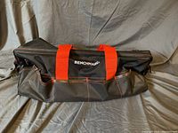 Closed large Benchmark tool bag with visible brand logo and red handles lying flat.